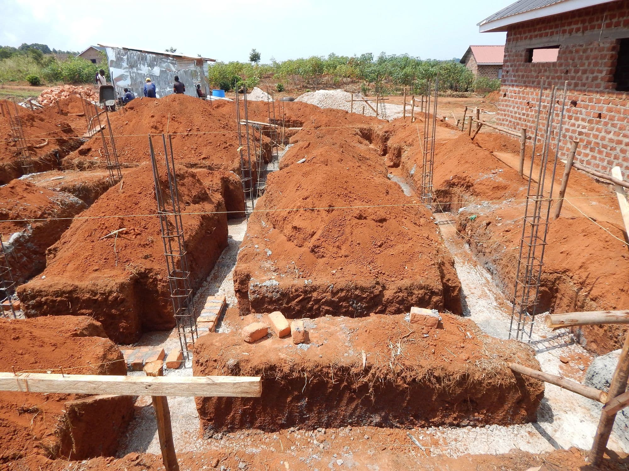 Valas de fundação abertas em terra vermelha, com armaduras de aço e gabarito de madeira.